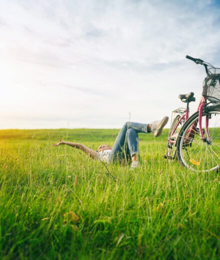 Jeune femme allongé dans un prés avec un vélo à coté