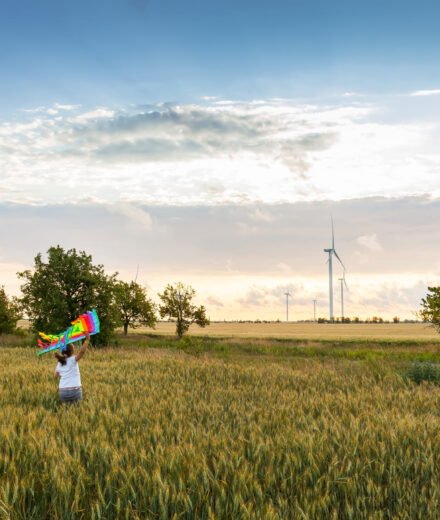 fille qui court dans un champ de blé avec son cerf volant dans la main