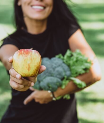 Femme qui tend une pomme avec un grand sourire